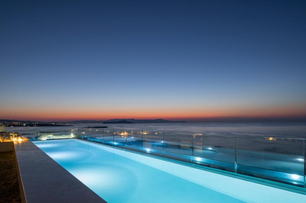 בריכת מלון אינפיניטי מול הים עם מעקה שקוף ושקיעה