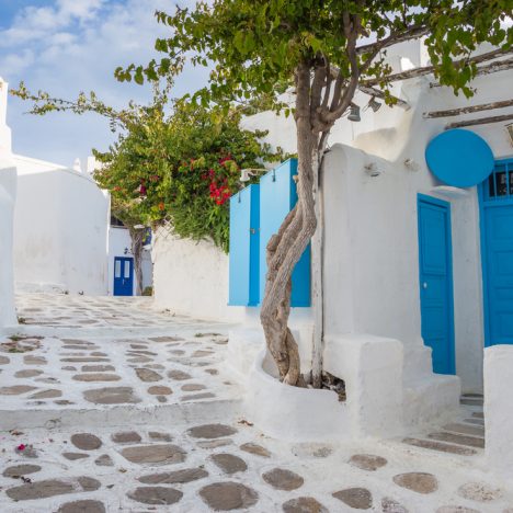 רחוב בעל מבנים לבנים ודלתות כחולות במיקונוס