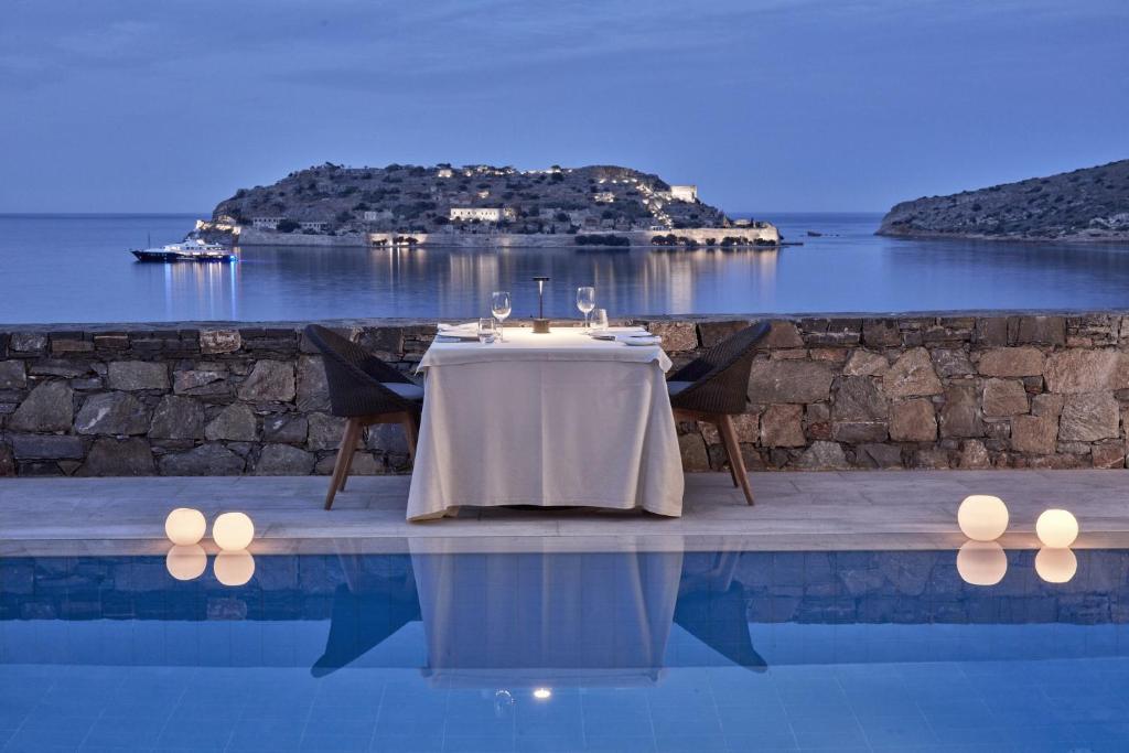 שולחן ושני כסאות על שפת בריכת המלון בלו פלאס עם נוף ערב רומנטי אל הים