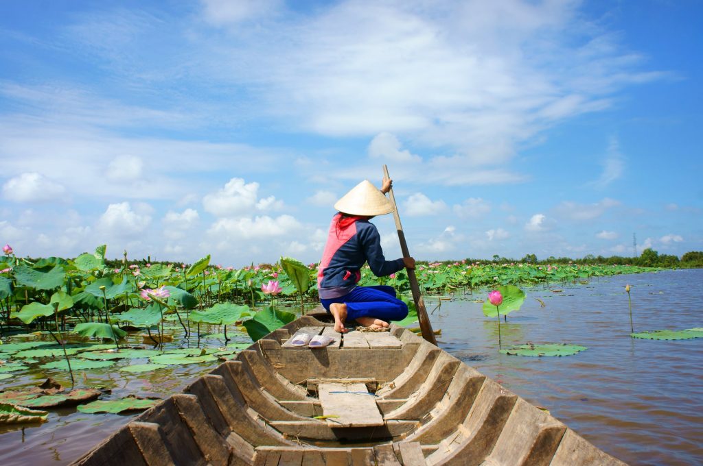 בן אדם על קצה הסירה בנהר בויאטנם עם פרחים עליו