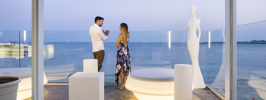 זוג עומד על מרפסת המלון אל מול נוף הים