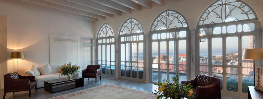 חדר לובי מרשים עם חלונות שקופים בצורה מעוגלת מקומות ישיבת ספות וכורסאות ונוף לעיר עכו והים