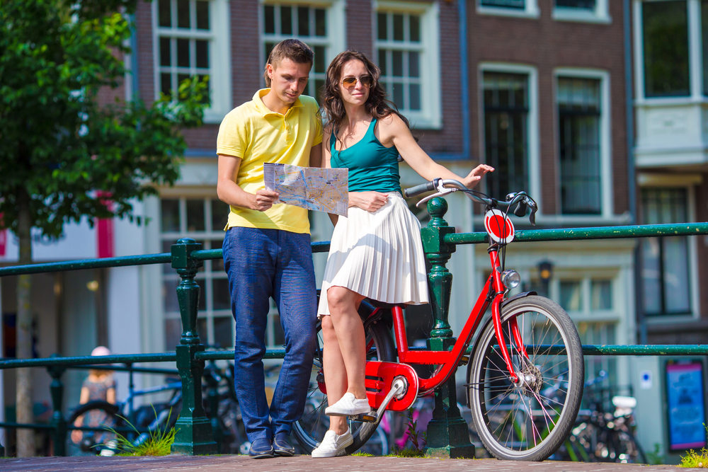 זוג באמסטרדם הגבר מסתכל במפה והאישה יושבת על האופניים