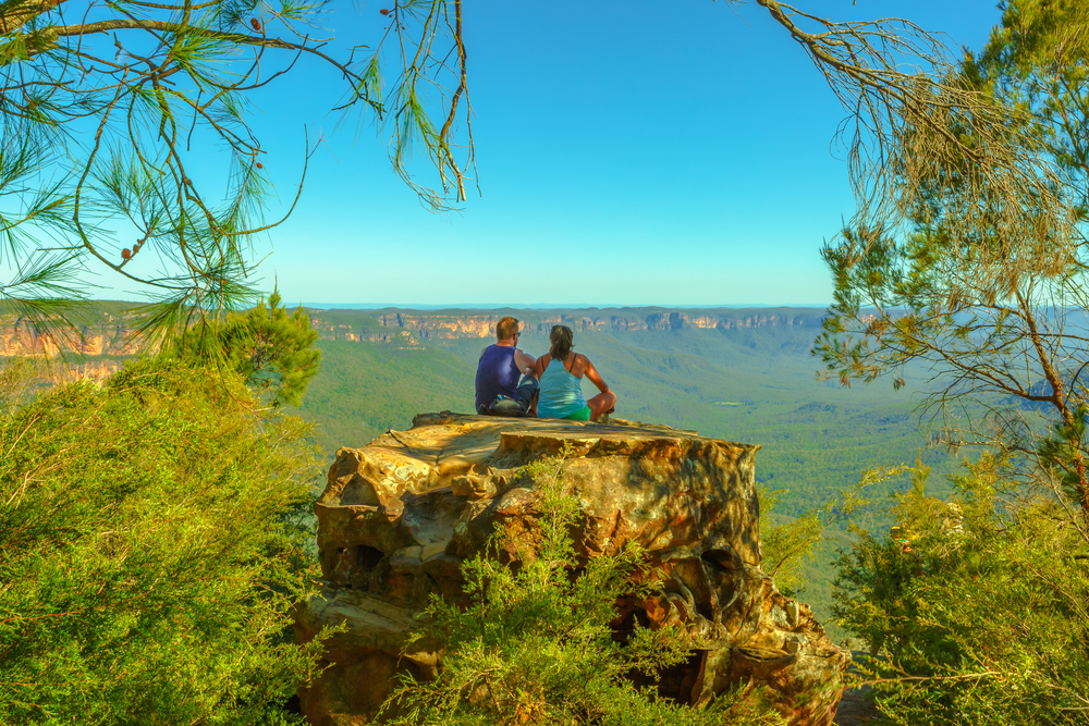  זוג יושב על סלע ענק ומשקיף לנוף הטבע באוסטרליה