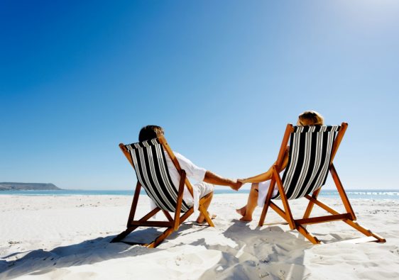 זוג יושב על כסאות חוף, חול לבן ונוף הים