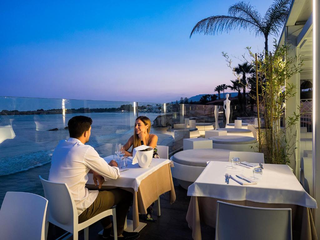 זוג התיישב לארוחת ערב מול נוף הים עם כוסות יין