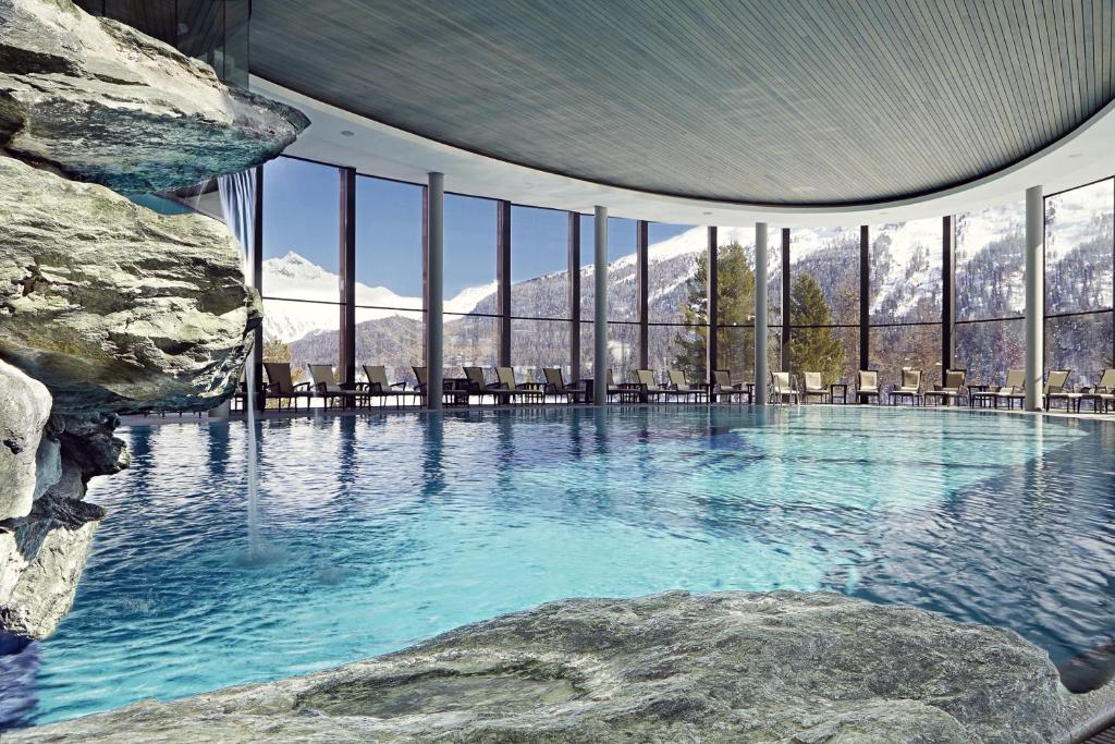 בריכת מלון סגורה עם חלונות זכוכית ענקיים שמשקיפים להרים מושלגים