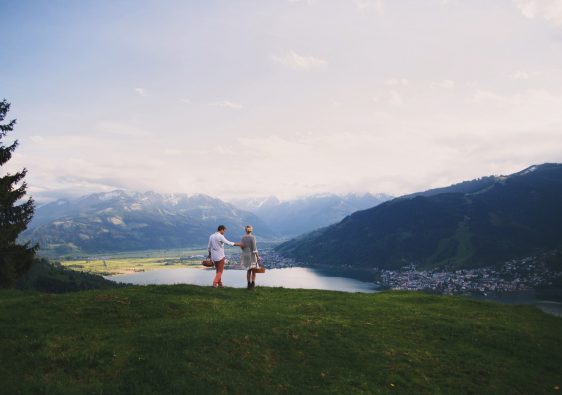 זוג מחזיק ידיים עם סלסלות פיקניק ונוף הרים וטבע של אוסטריה