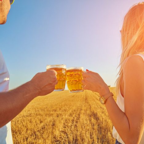 זוג עושה לחיים עם בירה מול שדה חיטה