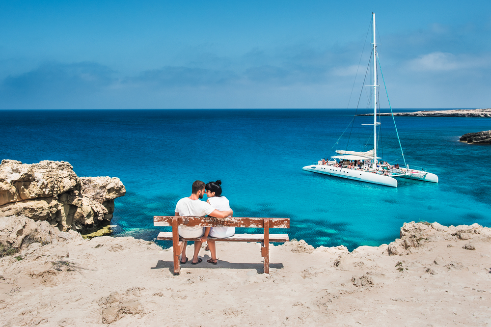 זוג יושב על ספסל מול נוף הים