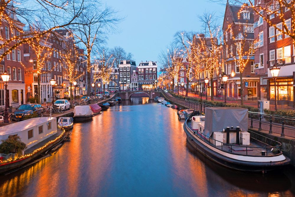 נהר באמסטרדם ובצידיו עצים מקושטים בנורות לד ורחובות העיר
