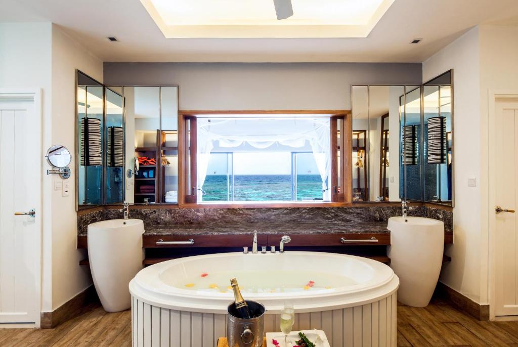 אמבטיה בחדר עם חלון שמקפיף לים ובקבוק שמפניה