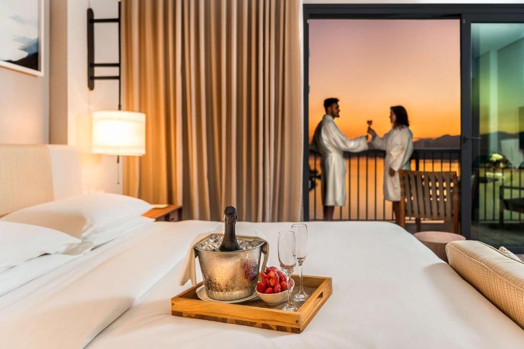 חדר המלון עם שמפניה על המיטה וזוג עושה לחיים במפרסת